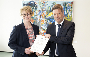 Der Bundesminister für Wirtschaft und Klimaschutz Robert Habeck (r.) überreicht Veronika Grimm (l.) die Urkunde. Foto: Bundesregierung / Guido Bergmann.